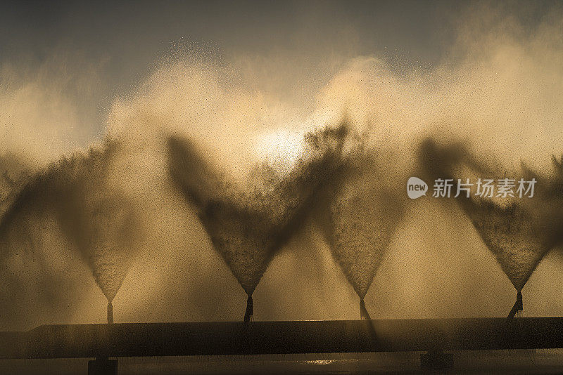 在热电厂的冷却池中，工业喷泉喷出的水花在阳光下闪闪发光。