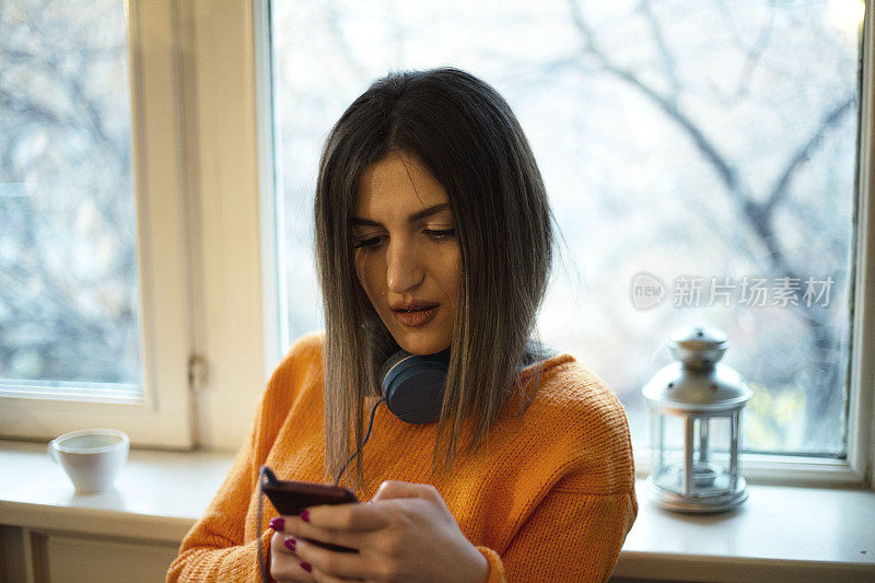 漂亮的年轻女子在窗户附近用手机