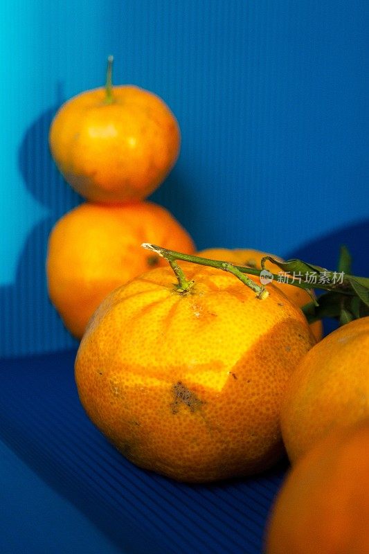 蓝纸背景下多汁的橘子和桔子，