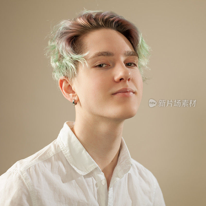 一个十几岁男孩的工作室肖像与绿色的头发在米色的背景