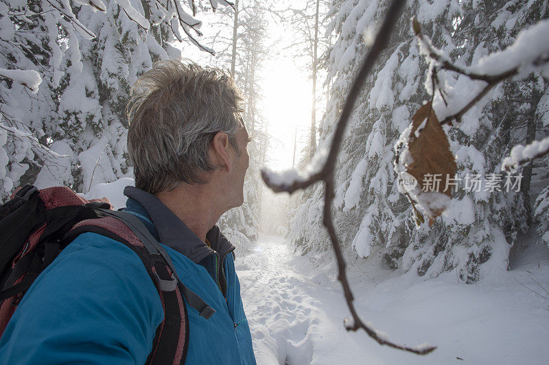 男性徒步旅行者在被雪覆盖的小径上行走