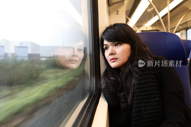 一幅亚洲妇女独自乘火车向窗外看的肖像