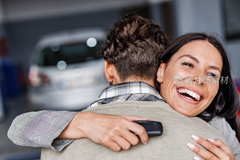 这对幸福的情侣在购买新车后拥抱在一起。