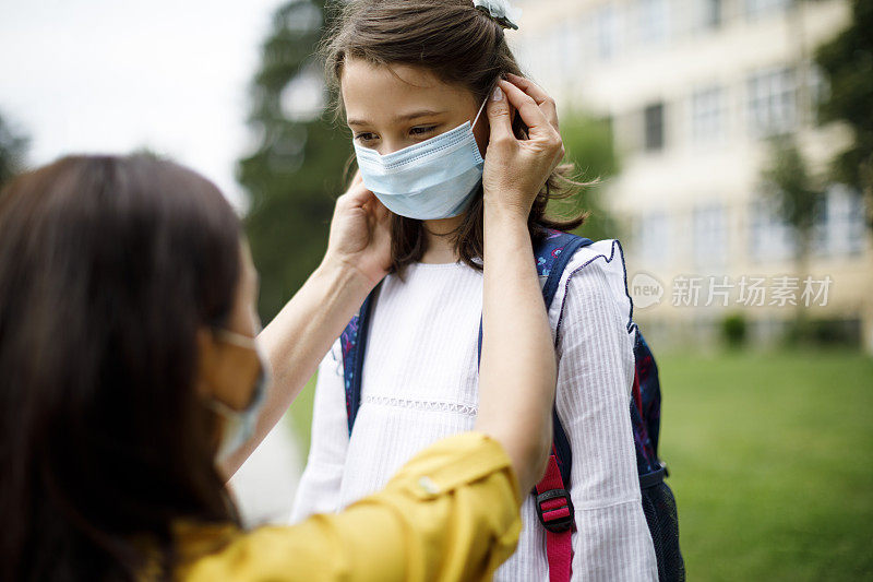 妈妈在学校前面为女儿准备上学