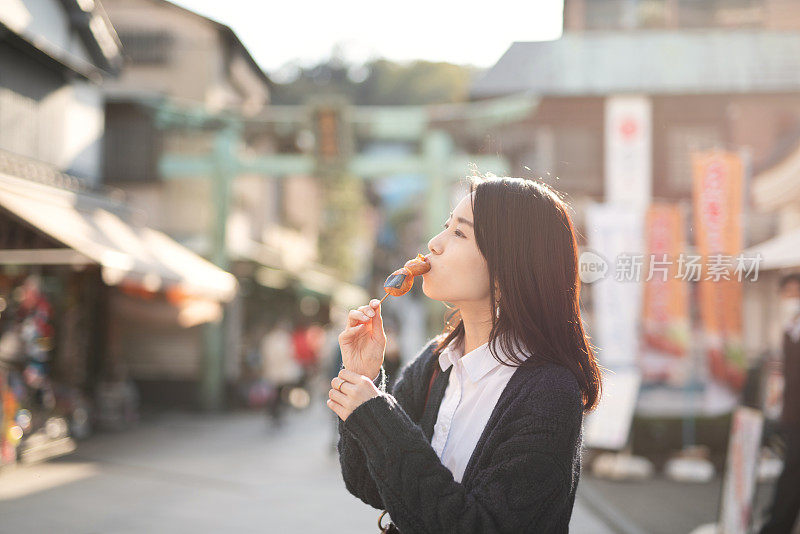 年轻的女游客在旅游目的地的街道上吃着外卖