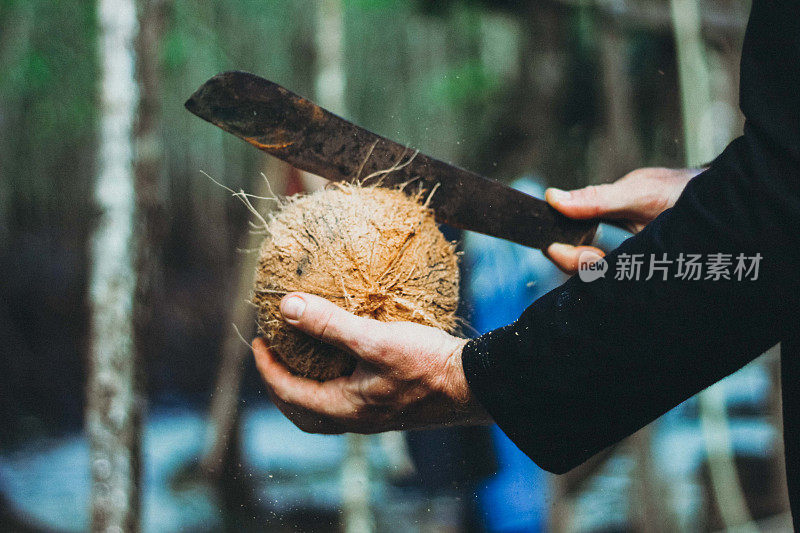 一个男人正在用大砍刀切开椰子