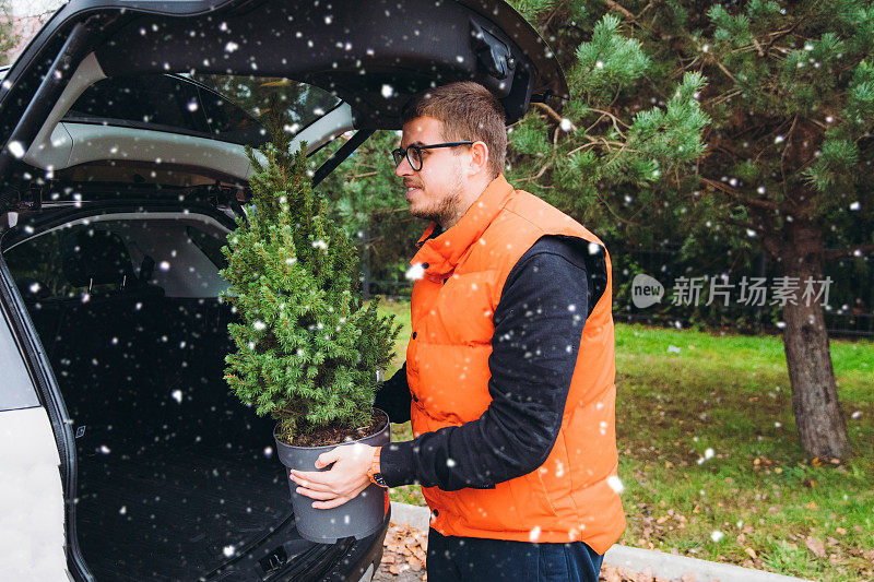 年轻微笑的男子正在为圣诞节的第一场雪做准备