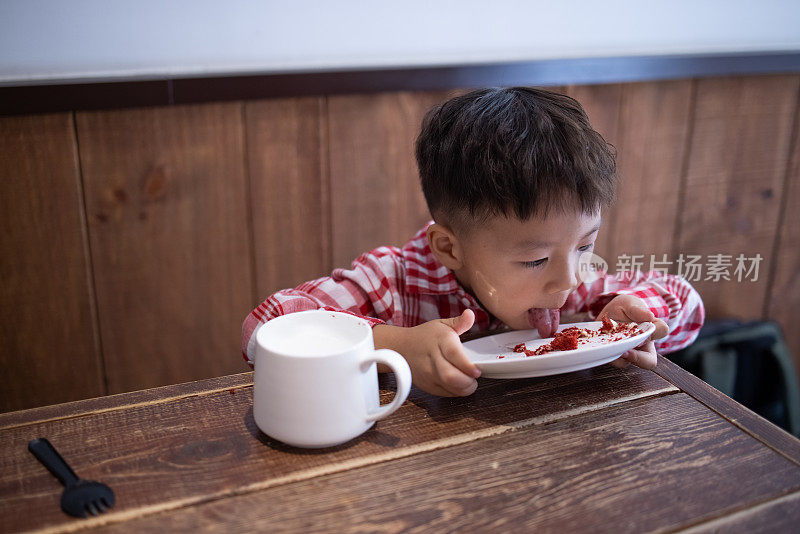 这个小男孩吃蛋糕，喝牛奶
