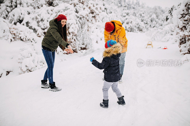 在一个美丽的冬天，年轻快乐的家庭一起在户外玩雪