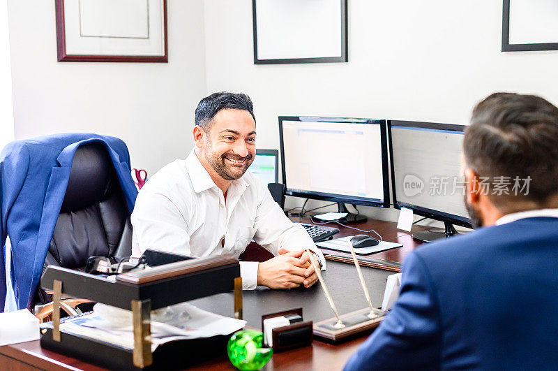 微笑的商人在他的办公桌上与一个客户开会