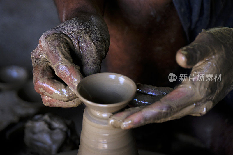排灯节前，一个陶工在他的住所的陶工转盘上准备陶罐。一位工匠在陶轮上塑造陶土花瓶的湿手。