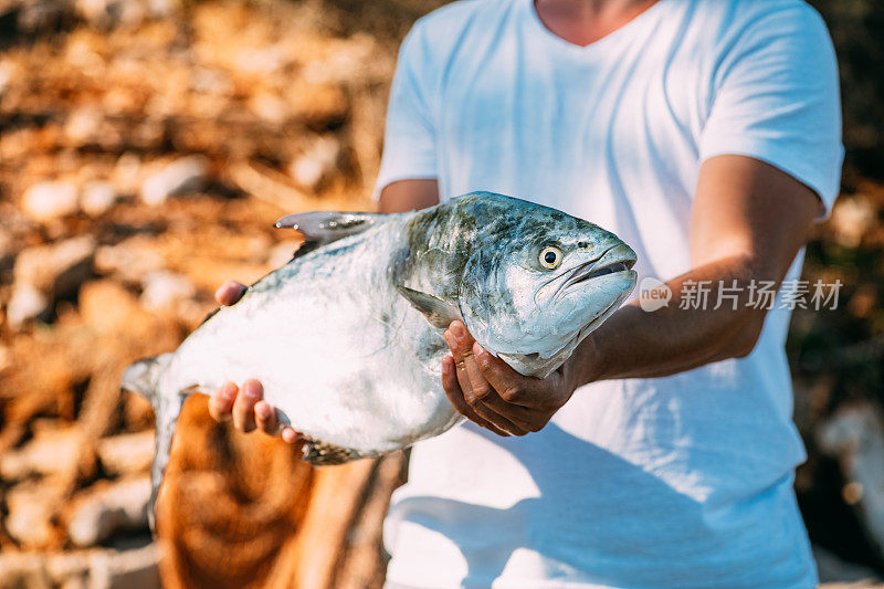 《年轻人和他钓到的斜纹鱼