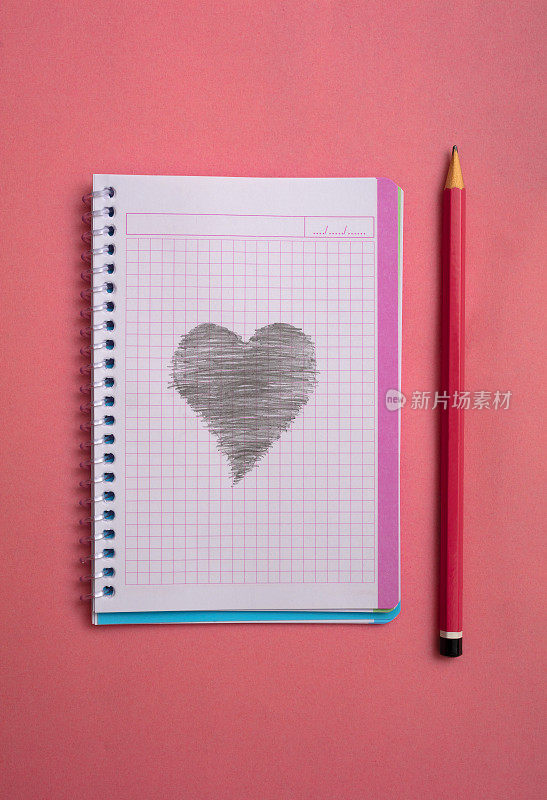 粉红色的背景上放着一本空白的笔记本和一支铅笔