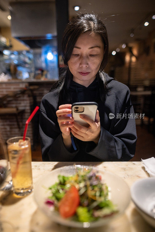 在餐厅用智能手机的女人