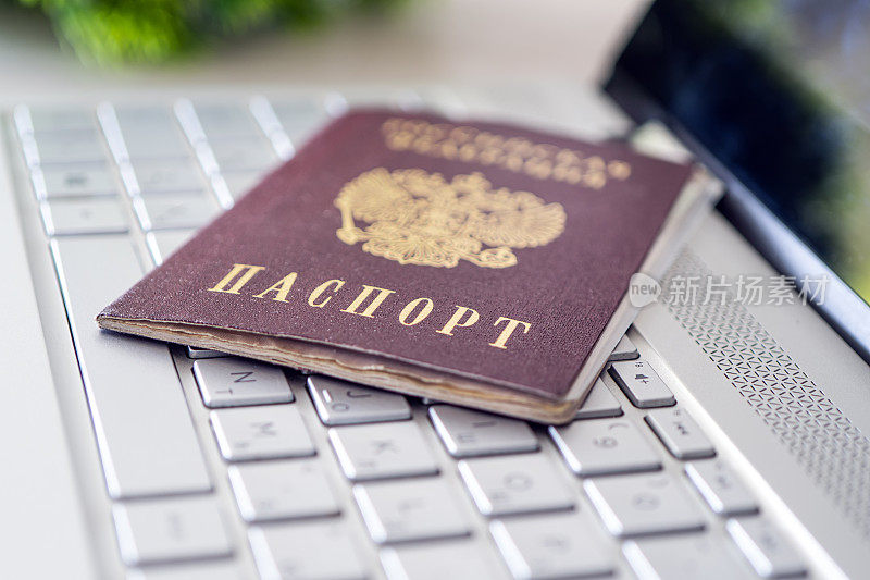 灰色笔记本电脑键盘上的俄罗斯联邦护照。互联网上用户的身份识别。禁止在没有护照数据的情况下上网。通过互联网发放护照