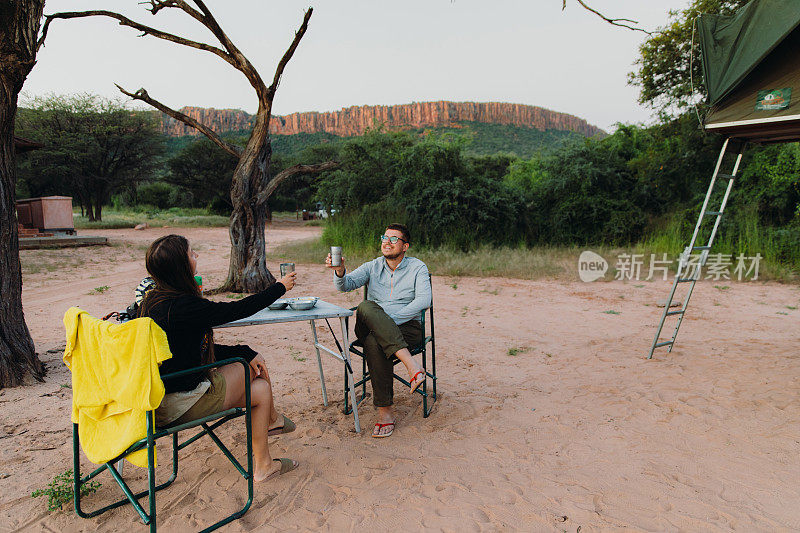 女人和男人旅行者考虑日落露营在纳米比亚的山景