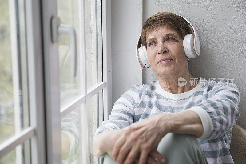 音频愈合。概念没有压力。老妇人戴着耳机在家听音乐。