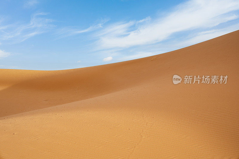 摩洛哥梅佐加沙漠的橙色沙丘和多云的天空。