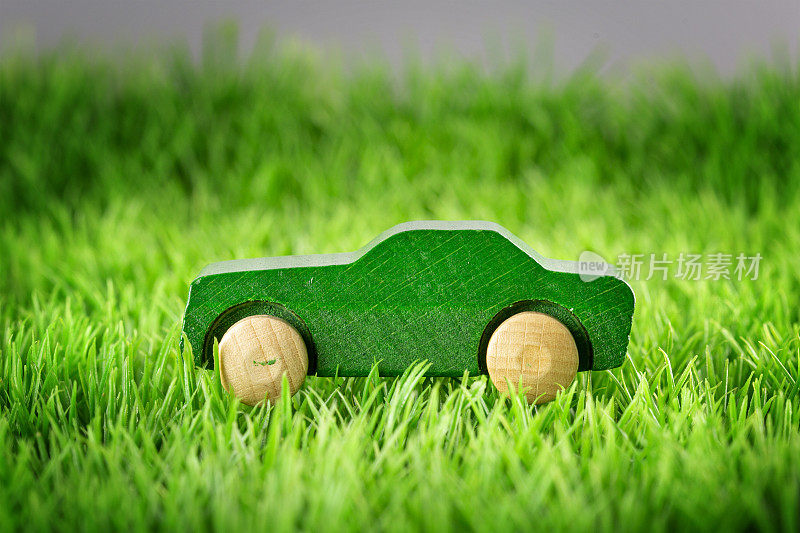 绿色草地上的木制玩具车-可持续移动的概念