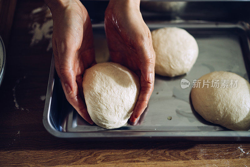 将面团放入金属托盘准备烘焙的手的特写