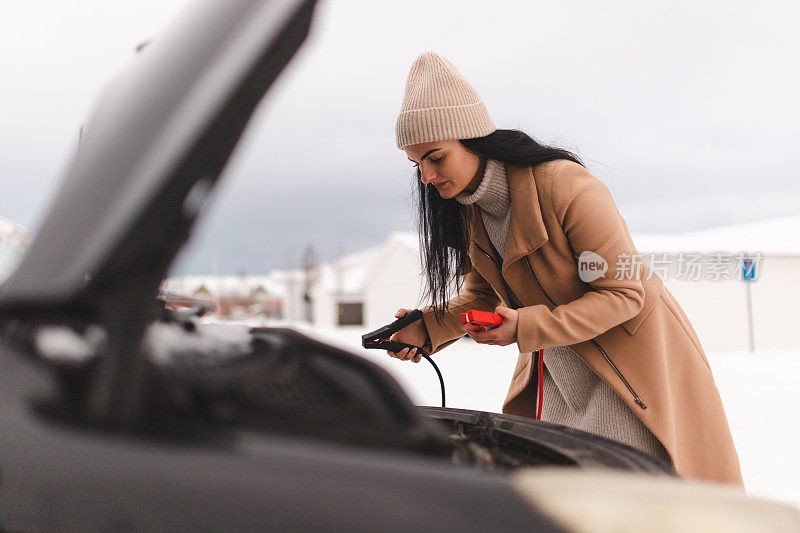 美丽的年轻女子试图跳启动她的车，因为电池没电了