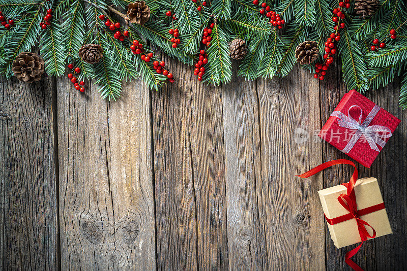 圣诞礼盒和冷杉树、冬青浆果在质朴的木头上复制空间背景