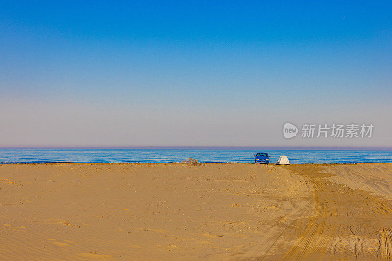 汽车停在海边的沙滩上对着清澈的蓝天