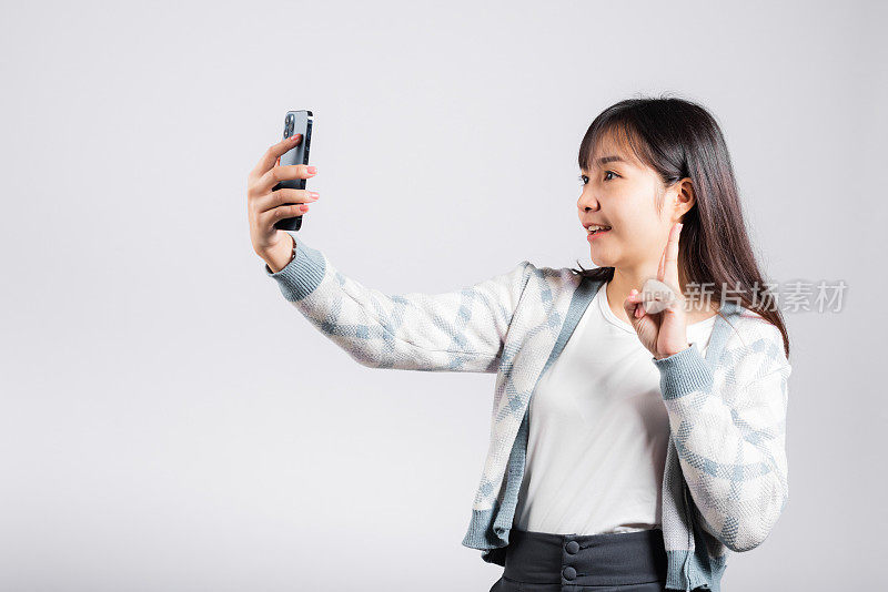 一名女子兴奋地拿着智能手机拍摄自拍照片