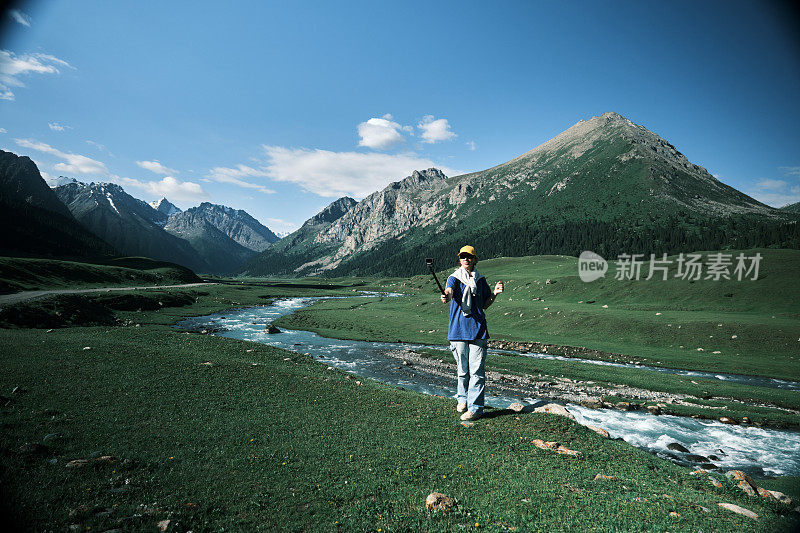 一位背包客正在拍摄她在山河上的旅行视频