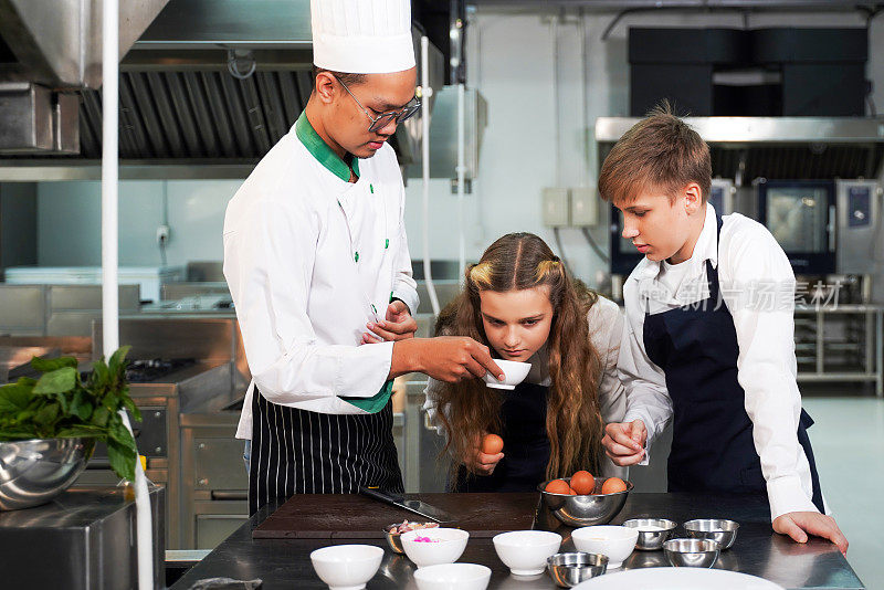 厨师老师在班级厨房教孩子们烹饪。厨师在工作坊指导学生学习标记和烹饪食物。教育的概念