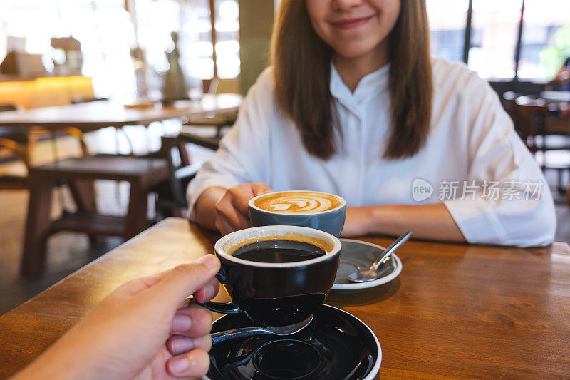 一个女人和一个男人在咖啡馆碰杯的特写照片
