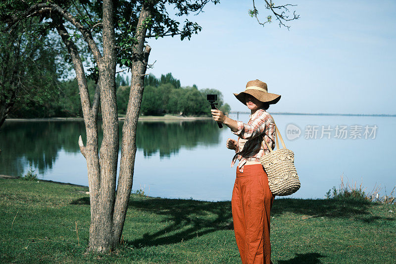 开朗的成熟女游客正在拍摄她的湖滨之旅