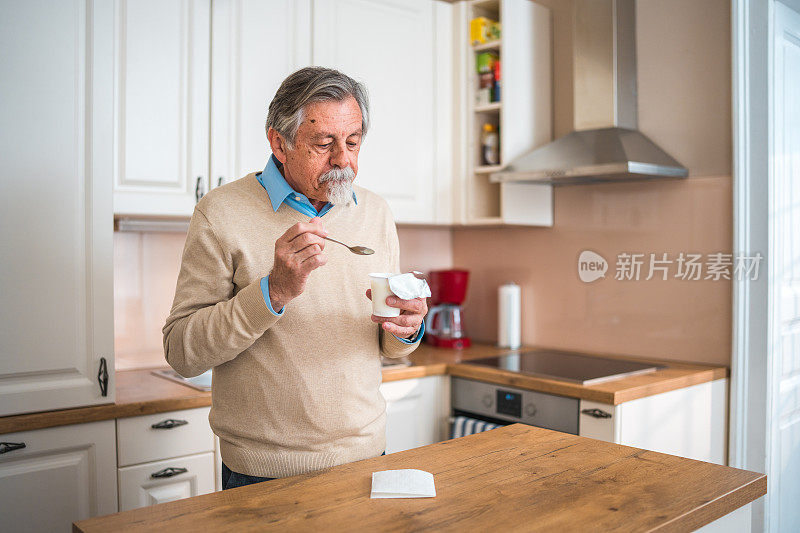 年长的白人男性在家享用酸奶