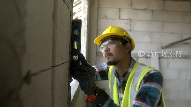 近景建筑师亚细亚用水位测量仪安装窗户施工现场。