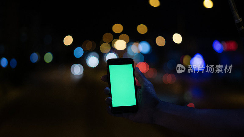 男人晚上用绿屏的智能手机