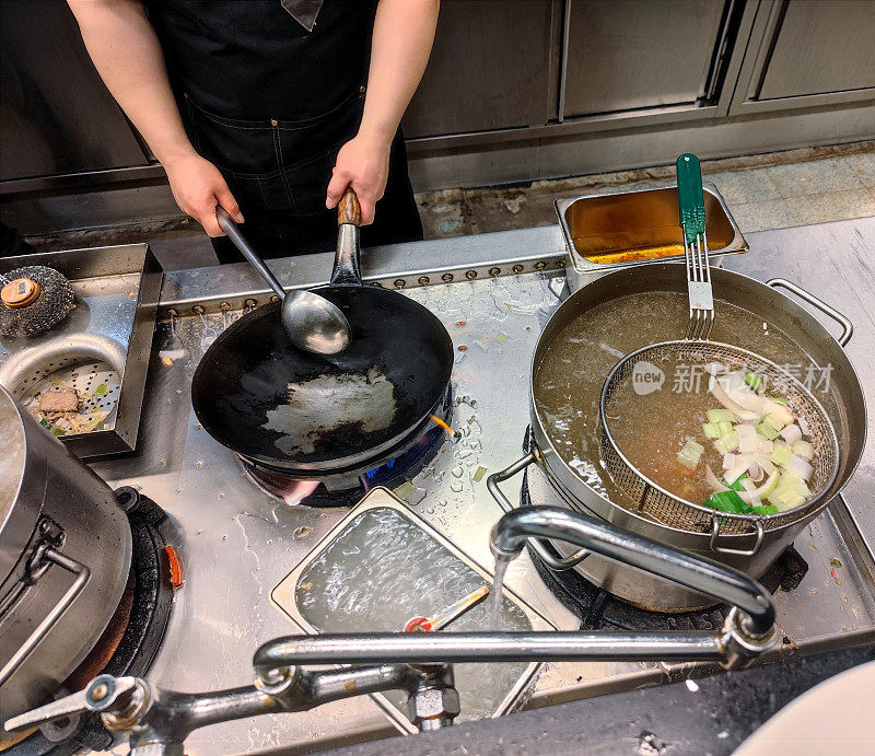 在亚洲的自助餐馆里，专业厨师正在准备和加热煎锅，然后把煮熟的蔬菜和肉放进去