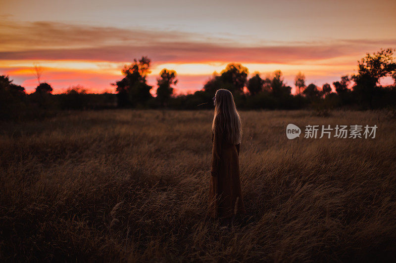 穿黄色衣服的金发女人躺在河岸上。夕阳的光。夏天的一天。长头发的。沙子。破碎的心