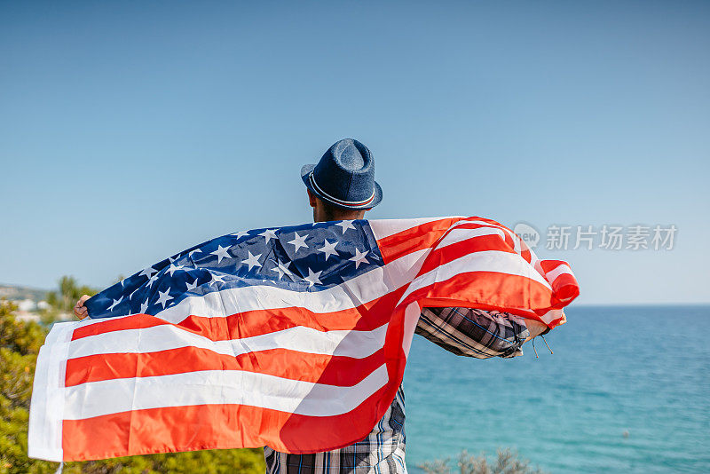 举着美国国旗的年轻人看着海岸线