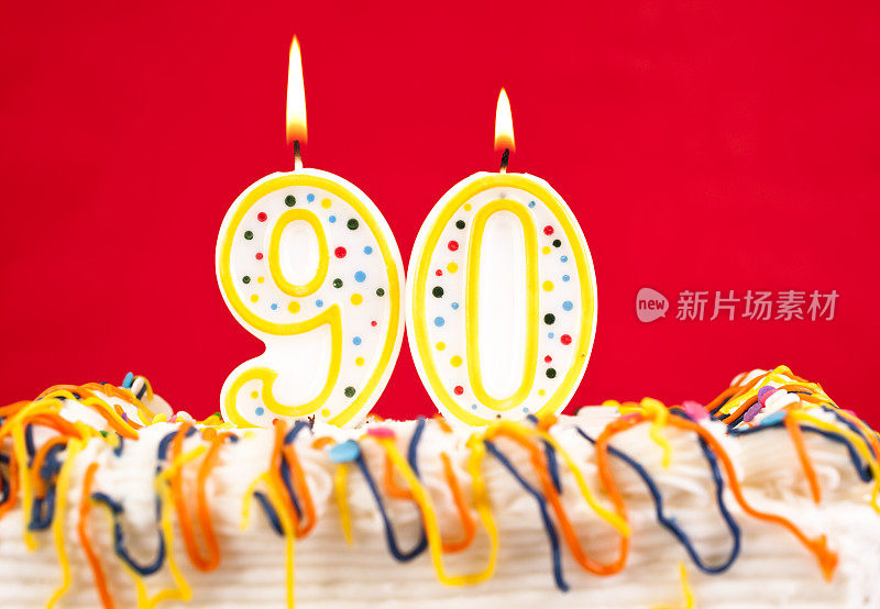 用90号燃烧的蜡烛装饰生日蛋糕。红色的背景。