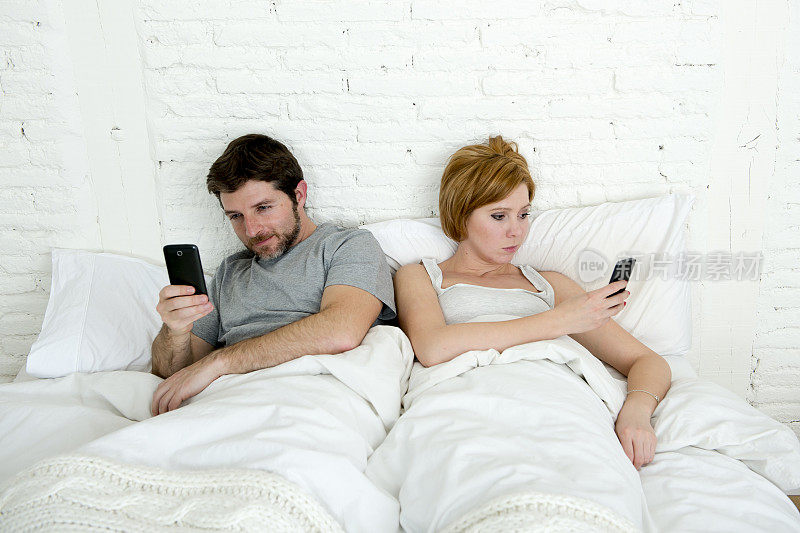 夫妻在床上玩手机，忽略对方