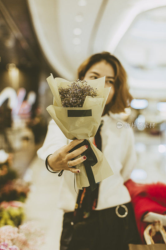 一个女人在花店外捧着一束花