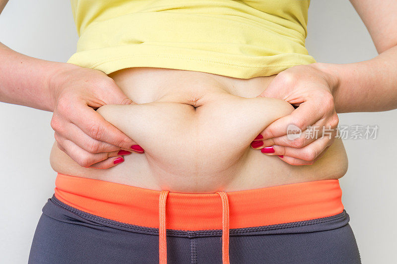 超重的女人用手触摸身体腹部的脂肪