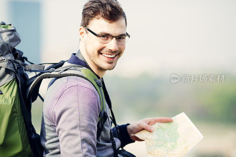 正在看地图的开朗男性背包客。