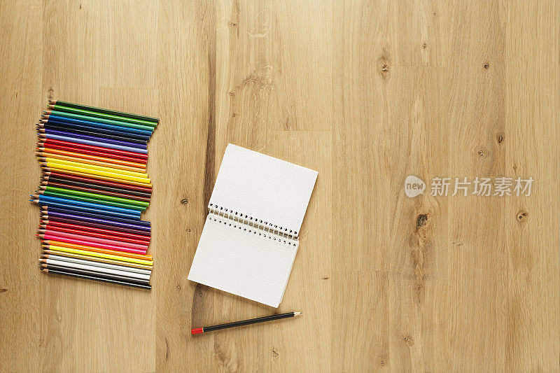 空白记事本与彩色铅笔在木地板拼花背景