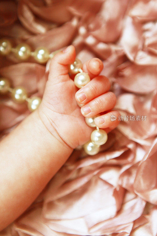 新生婴儿紧握珍珠的手