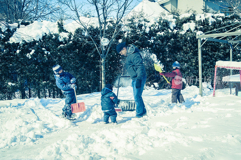 爸爸和儿子们在冰场铲雪。