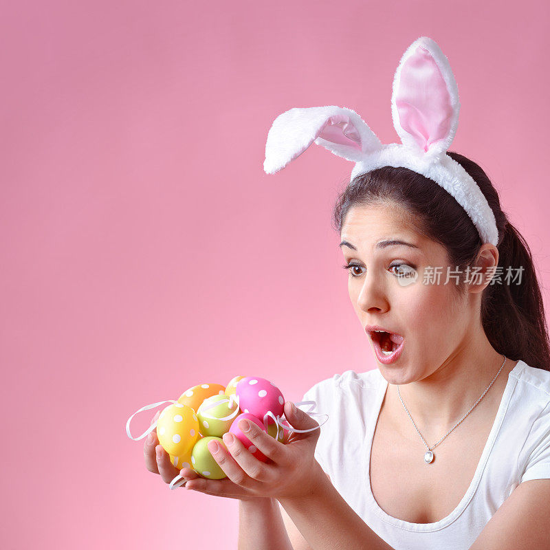 快乐的年轻女子戴着兔子耳朵，拿着复活节彩蛋