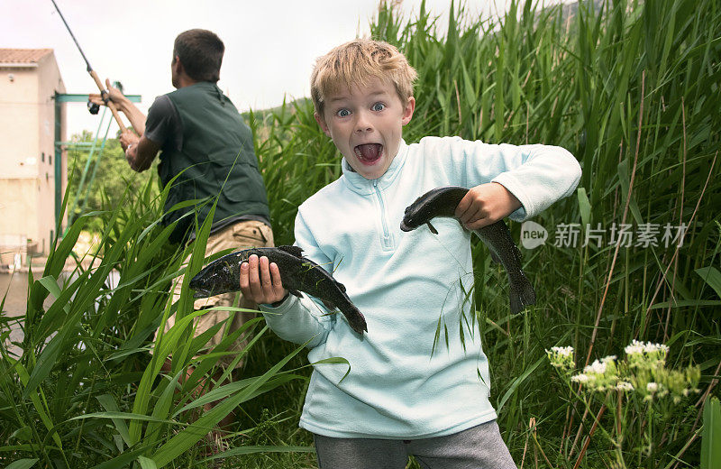 成功的孩子抱着他的第一条鳟鱼，和爸爸一起钓鱼