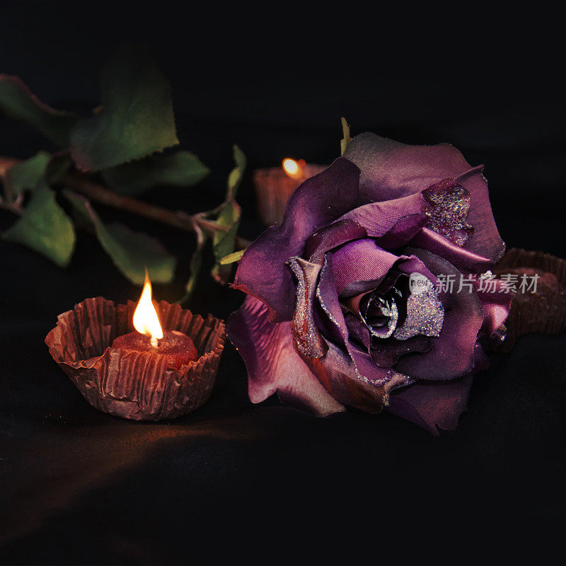 黑缎子上美丽的玫瑰和蜡烛。