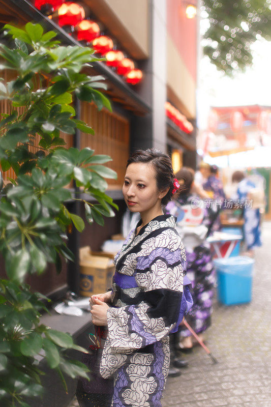 年轻的浴方女子站在石头铺的街道在夏季节日